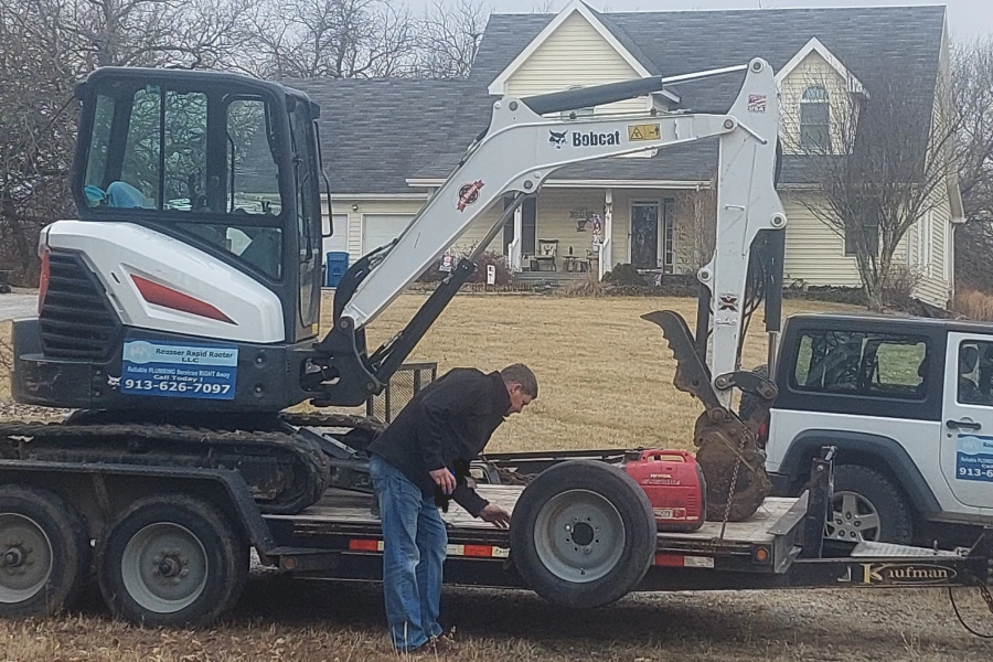 worker checking a white construction machine outside of a beige house and a big patio